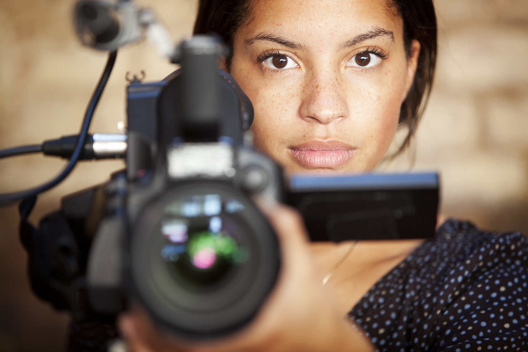 A confident glance from a video camera operator engaging eye contact with her subject during filming.